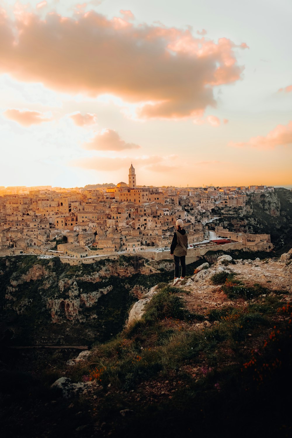 a man standing on top of a cliff overlooking a city