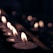 A warm, softly lit table setting featuring several tealight candles glowing gently in glass holders.