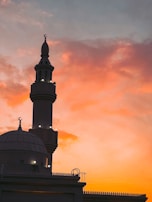 A peaceful sunset view of the mosque's exterior with its illuminated minaret.