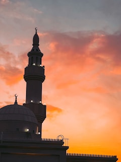 A view of a mosque at sunset, with vibrant colors in the sky.