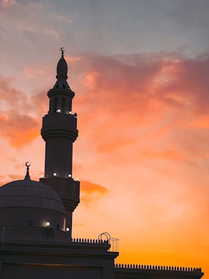 A peaceful sunset view of the mosque's exterior with its illuminated minaret.