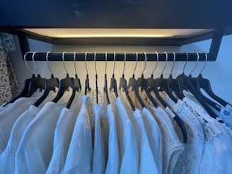 A neat row of colorful velvet, metal, and plastic hangers holding a variety of clothes in a bright, tidy closet.