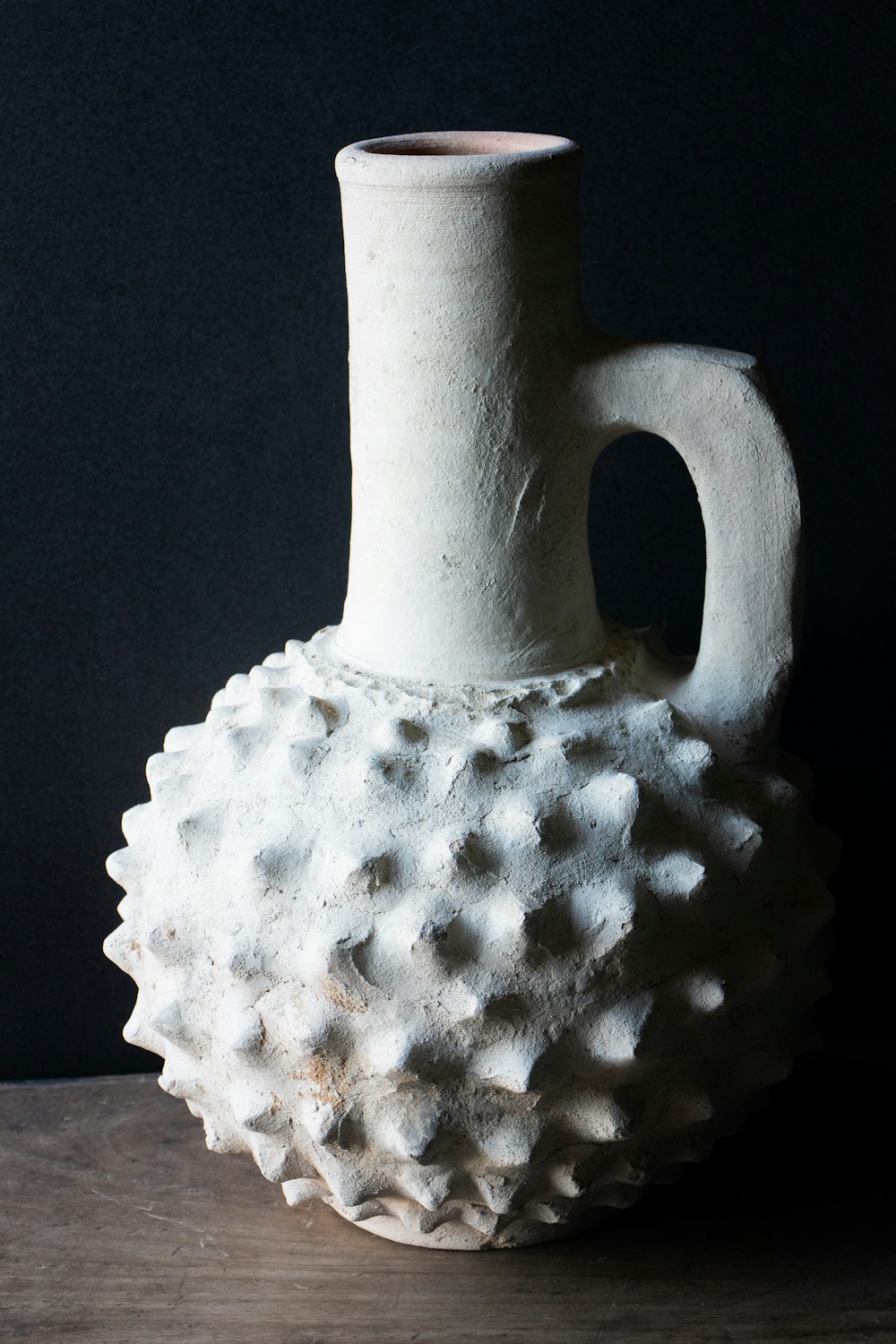 a white vase sitting on top of a wooden table