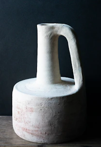 Traditional earthenware jug filled with amber-colored mead surrounded by wildflowers.