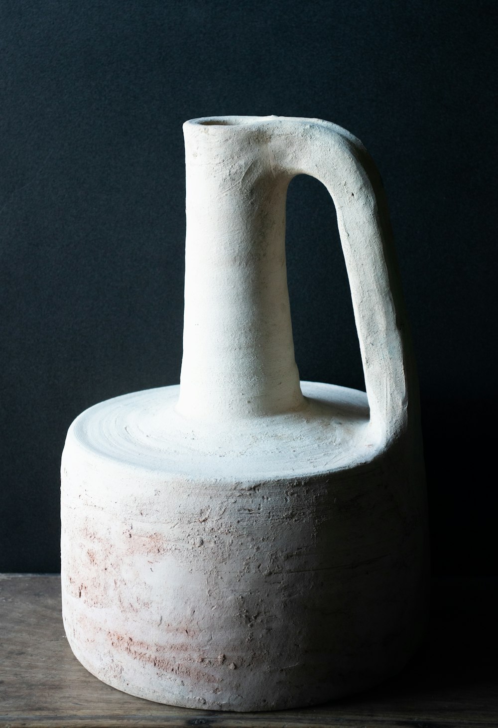 a white vase sitting on top of a wooden table