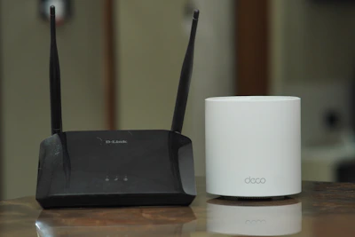 Compact Wi-Fi extender placed next to a laptop on a wooden table