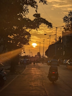 Wide shot of a rider in customized leather pants cruising down a scenic highway at sunset