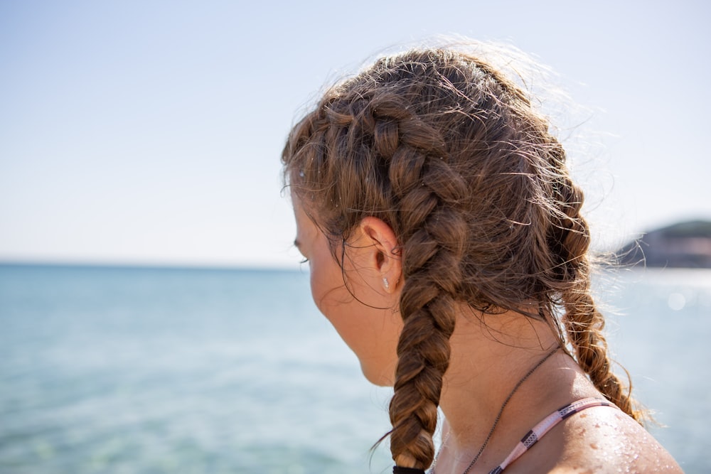 uma menina com uma trança em pé na praia