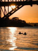 A vibrant sunset casting golden light over a group kayaking together along a coastal cove.