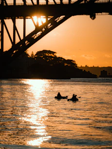 A vibrant sunset casting golden light over a group kayaking together along a coastal cove.