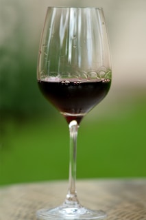 An elegant wine glass filled with red wine against a rustic background.