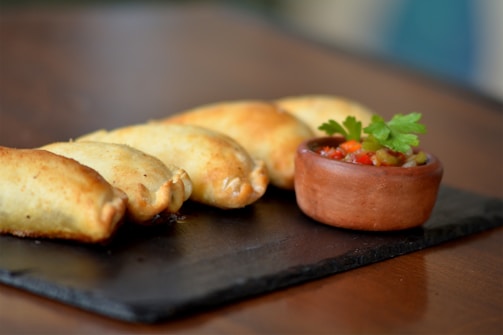 A vibrant display of empanadas with colorful fillings arranged on a rustic wooden board.