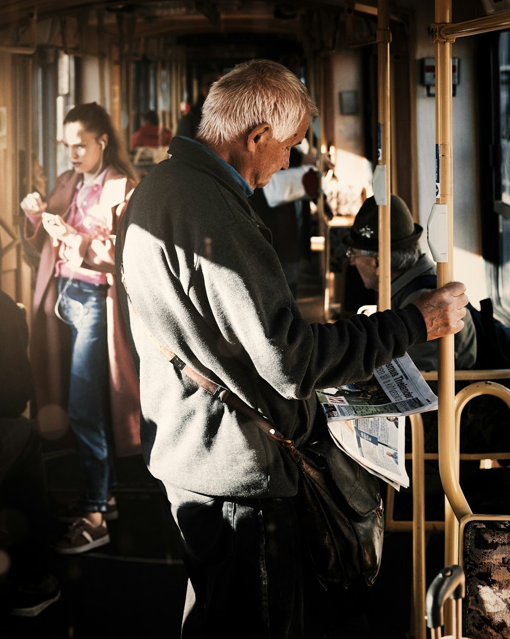 a man standing on a bus reading a newspaper