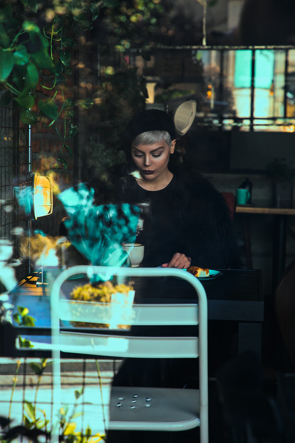 a woman sitting at a table in front of a potted plant