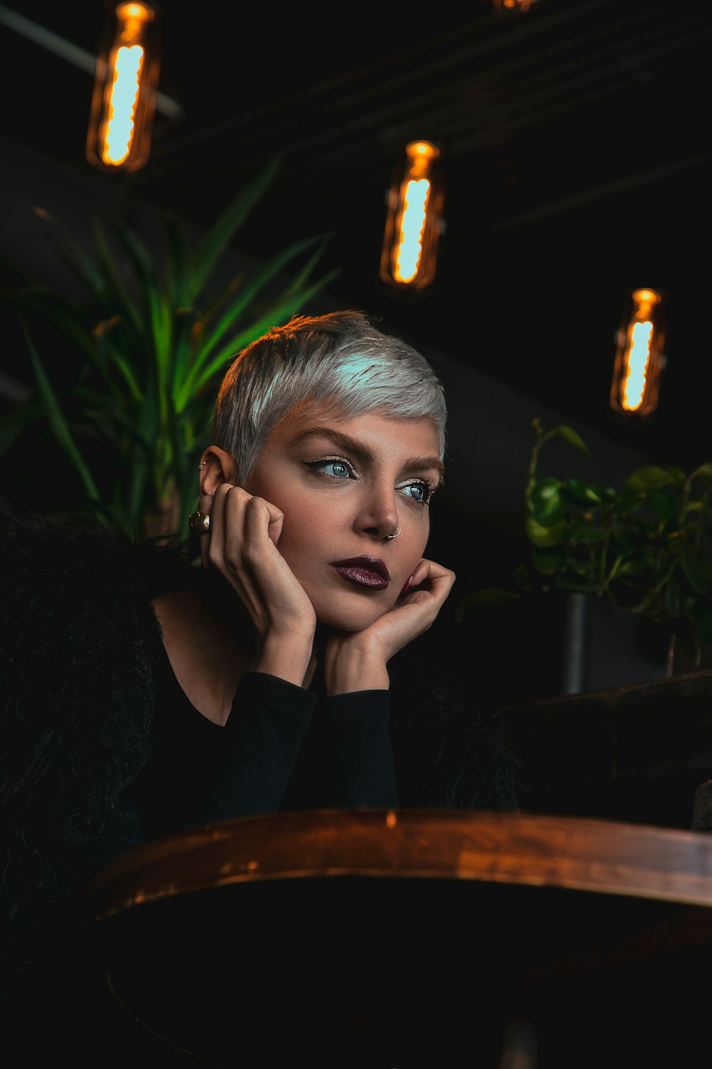 a woman sitting at a table with her hand on her chin