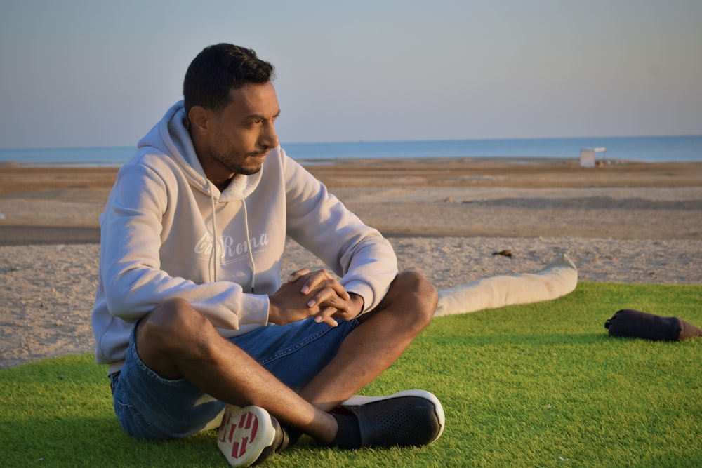 a man sitting on the grass on the beach