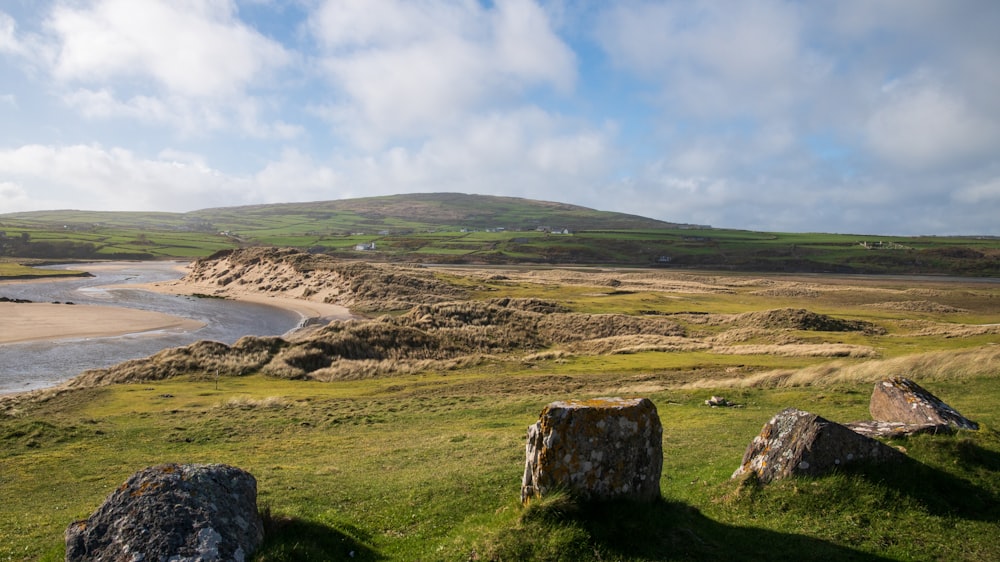 a grassy field with rocks and a body of water in the distance