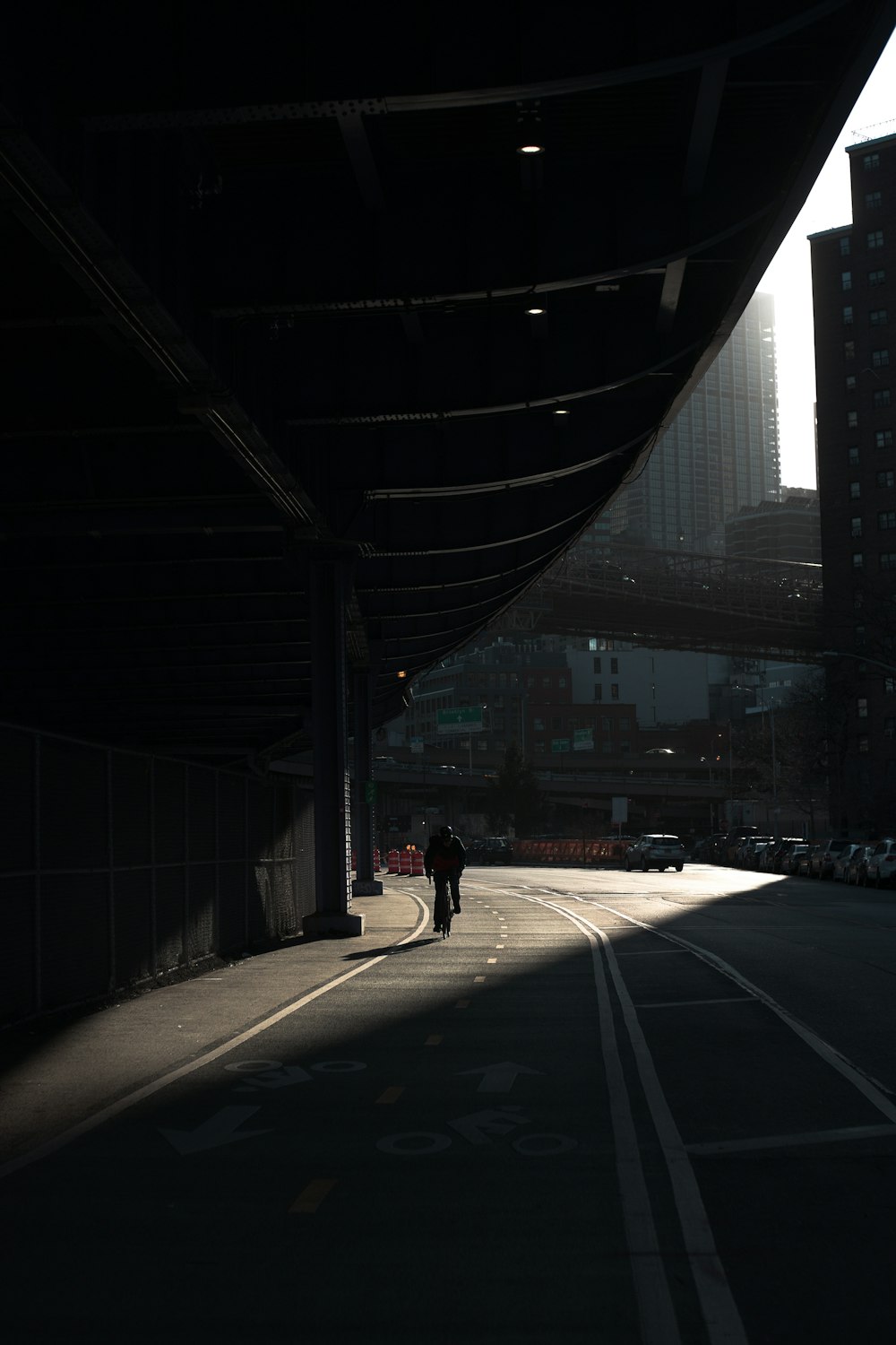 a couple of people walking down a street under a bridge