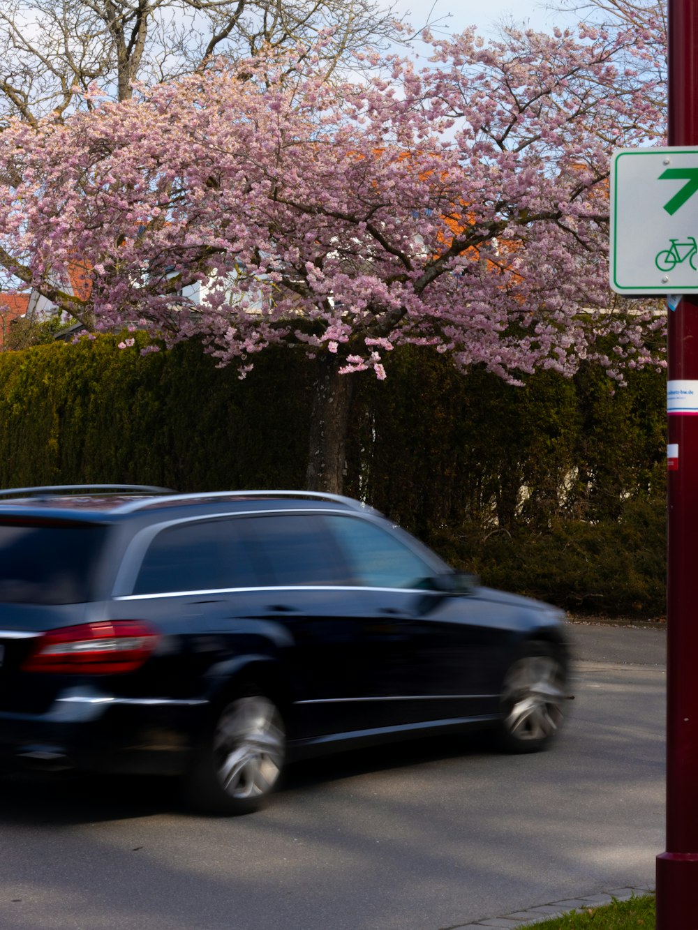 a black car driving down a street next to a tree