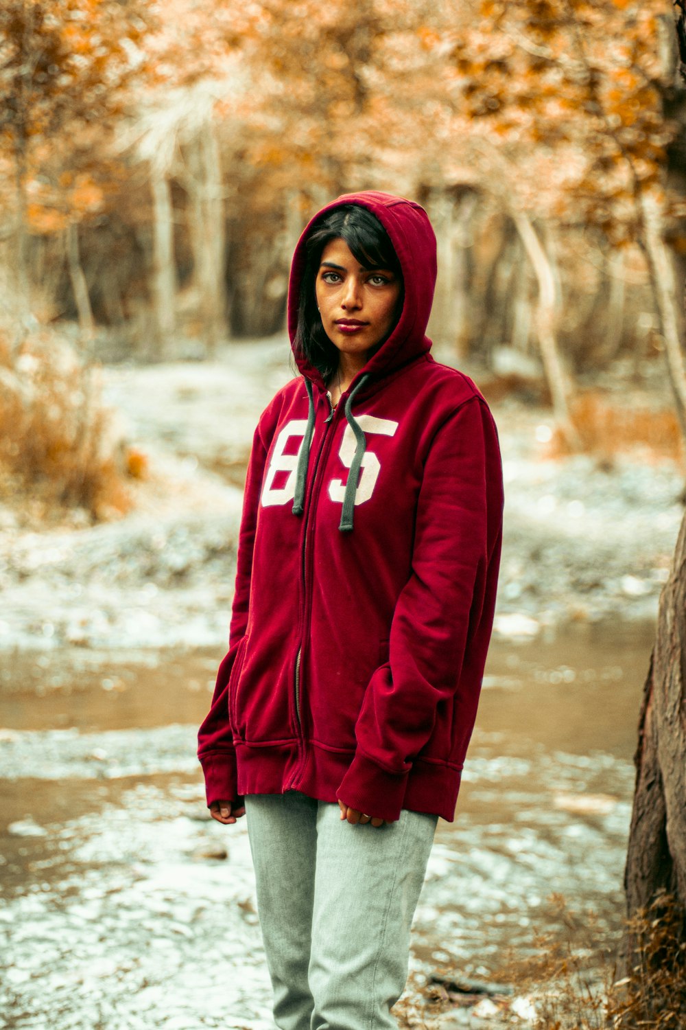 a man in a red hoodie standing in a stream