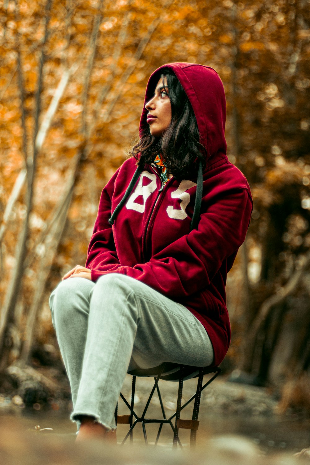 a woman in a red hoodie sitting on a stool