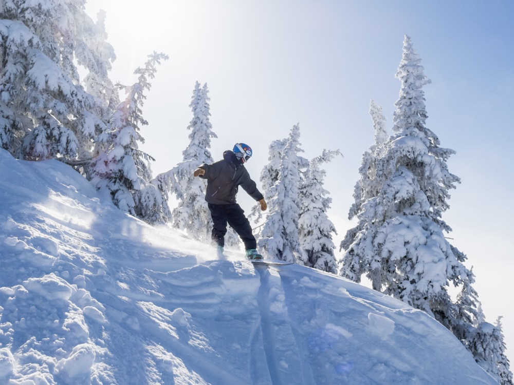 a man riding a snowboard down the side of a snow covered slope