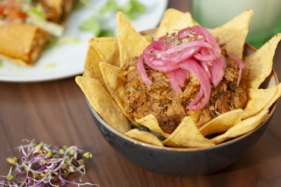 a bowl filled with tortilla chips topped with onions