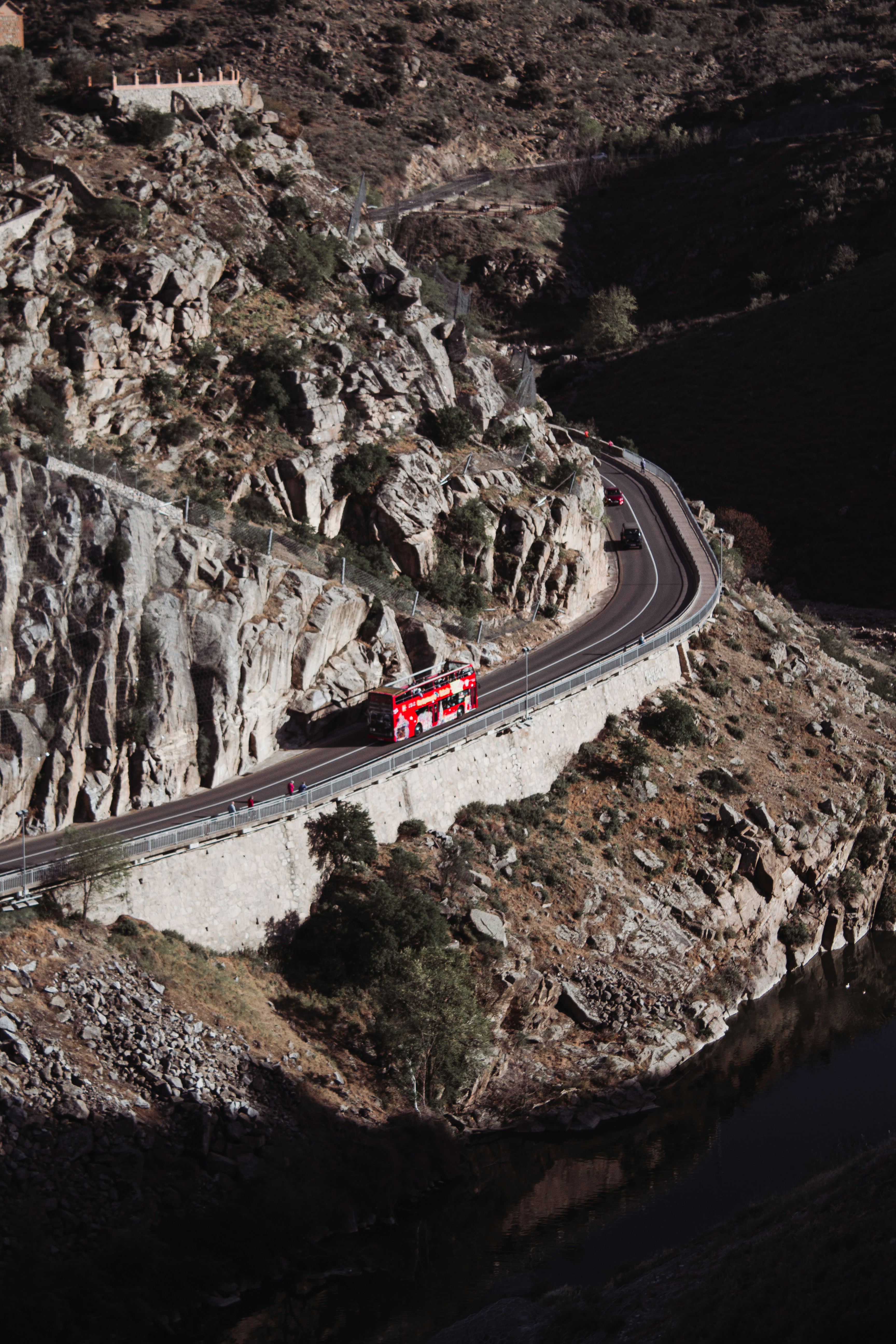 a red bus driving down a mountain road
