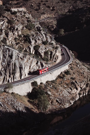 A modern minibus with panoramic windows cruising along a winding highway through hills.