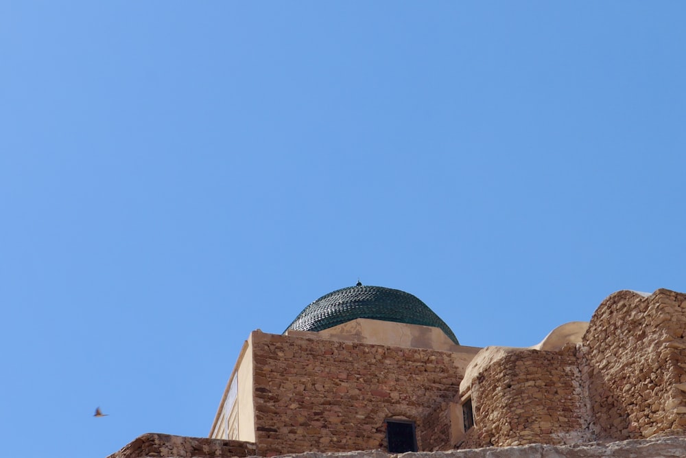 a tall brick building with a green dome on top