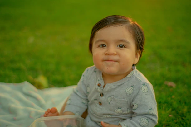 a baby sitting in the grass with a plastic container