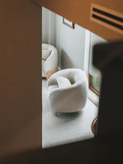 Cozy armchair with soft upholstery in a spacious white room with minimal decor.