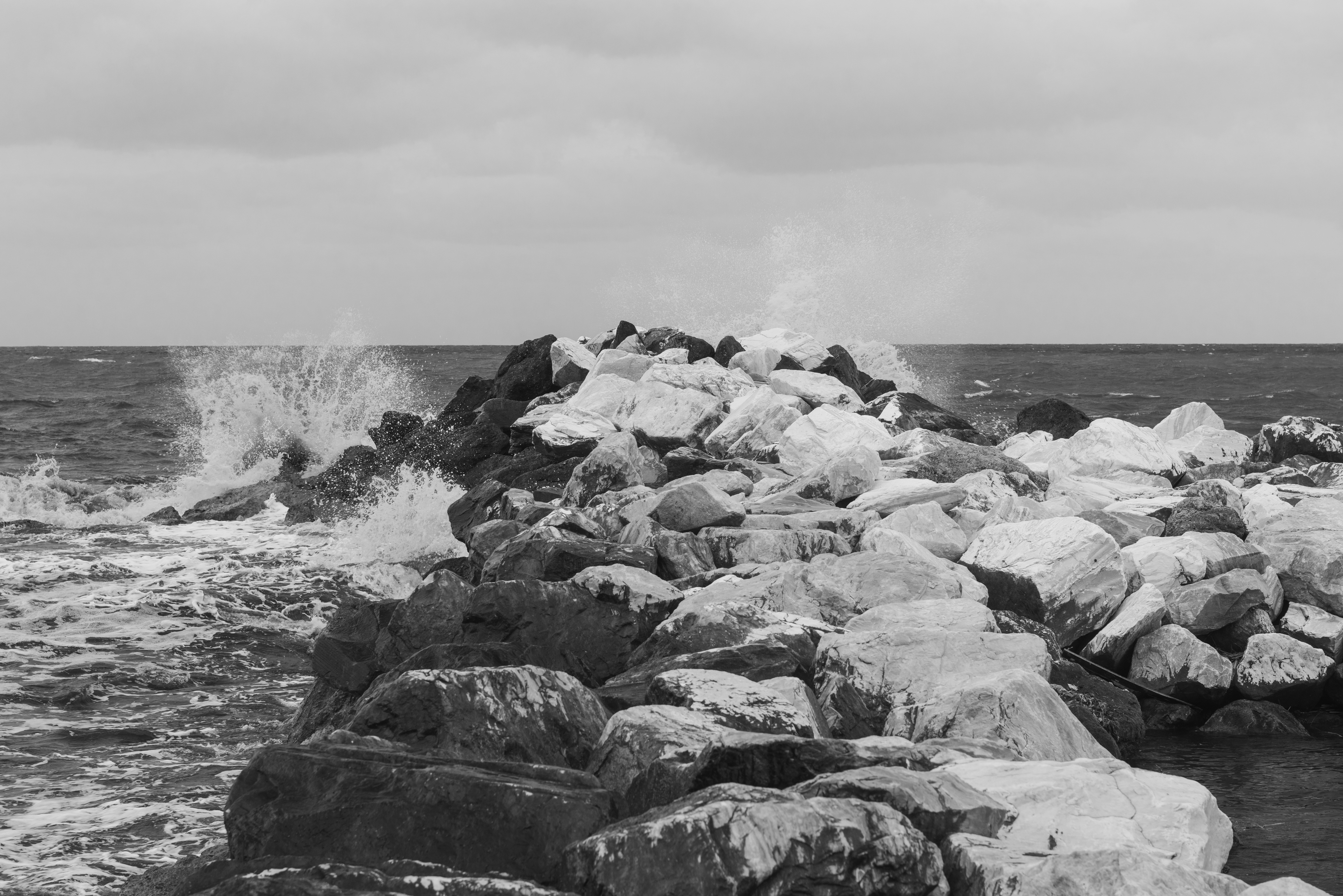 a black and white photo of waves crashing on rocks