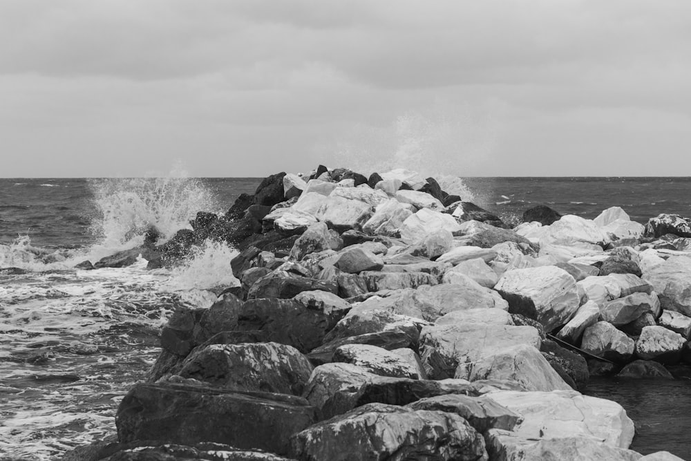 a black and white photo of waves crashing on rocks