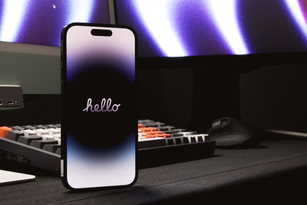 a cell phone sitting on top of a desk next to a keyboard