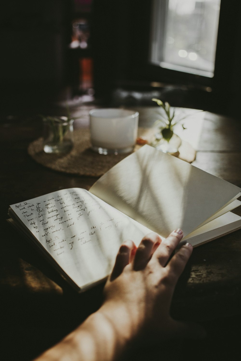 a person's hand holding an open book on a table