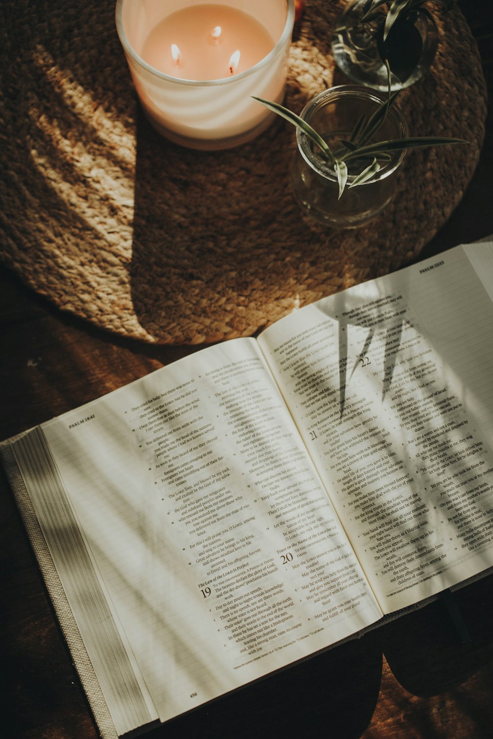 an open book sitting on top of a table next to a candle