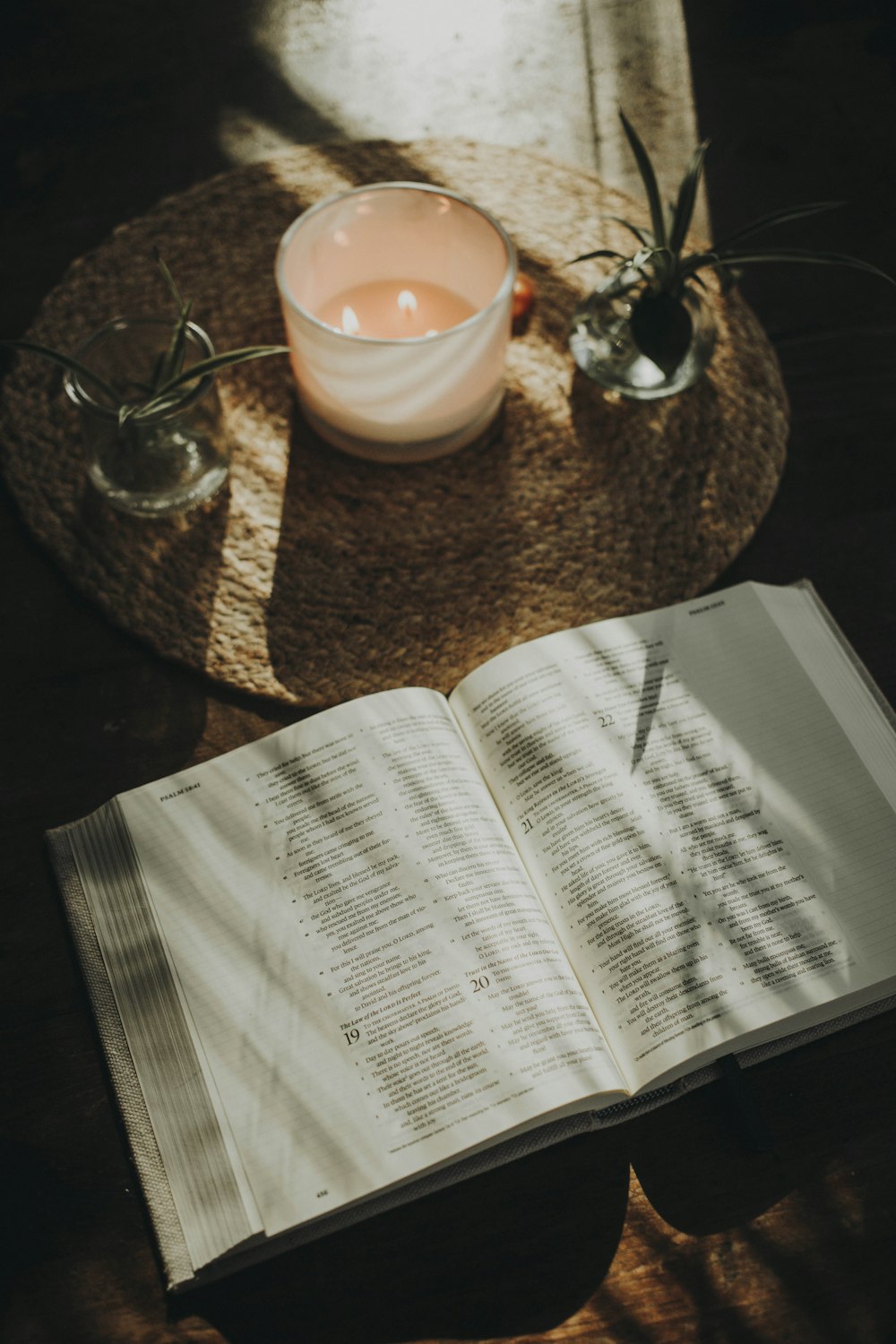 an open book sitting on top of a table next to a candle