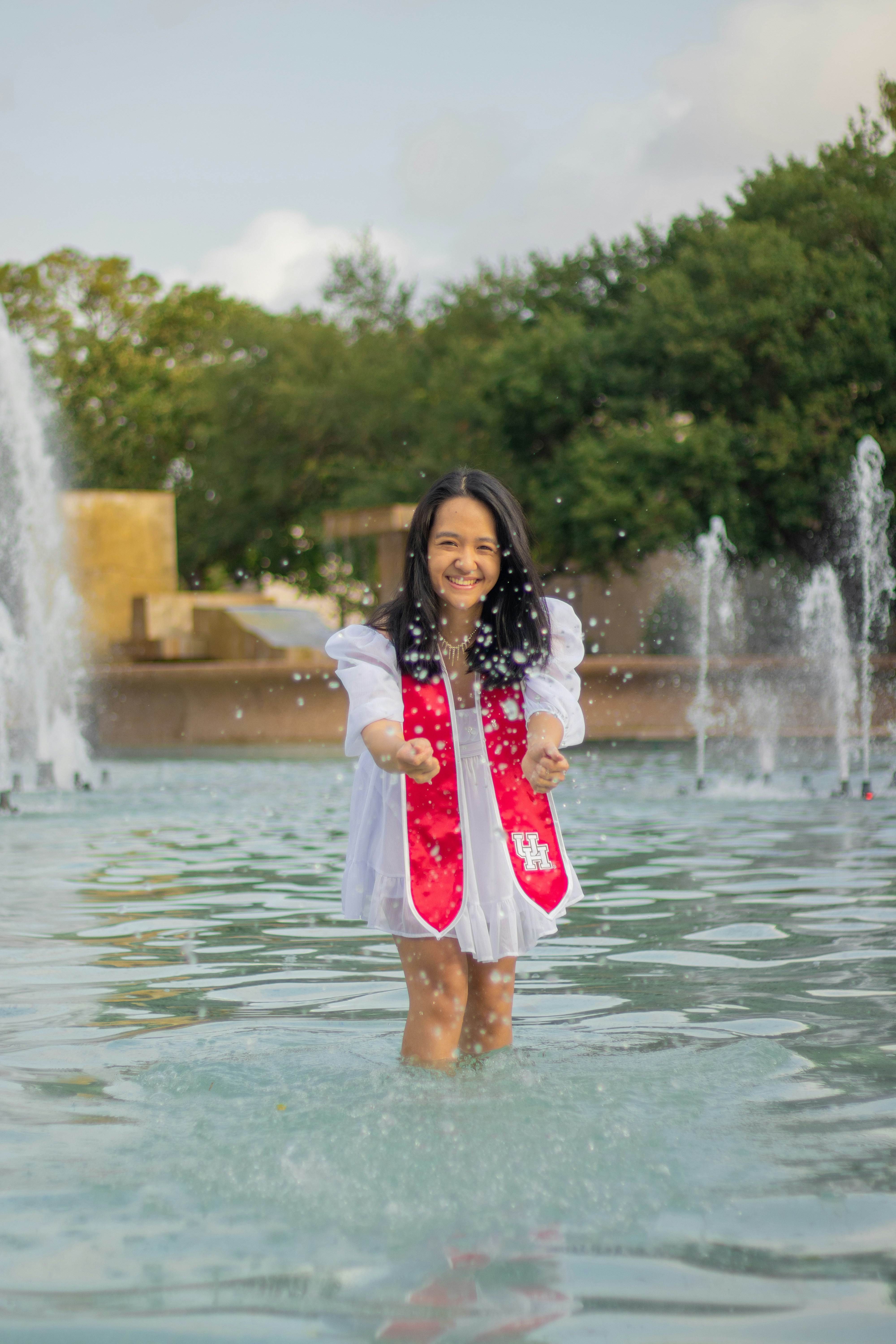 une fille en robe blanche debout dans une fontaine