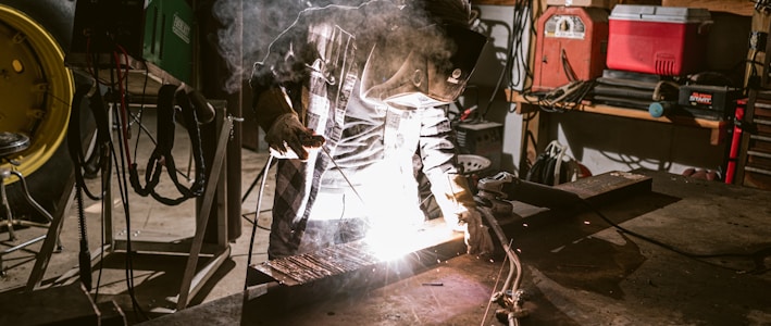 a man working on a piece of metal in a garage