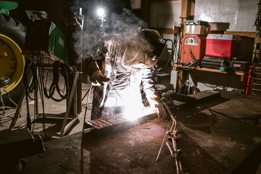 a man working on a piece of metal in a garage