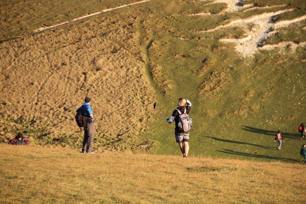 a group of people walking across a grass covered hillside