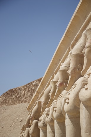 a row of statues in front of a pyramid