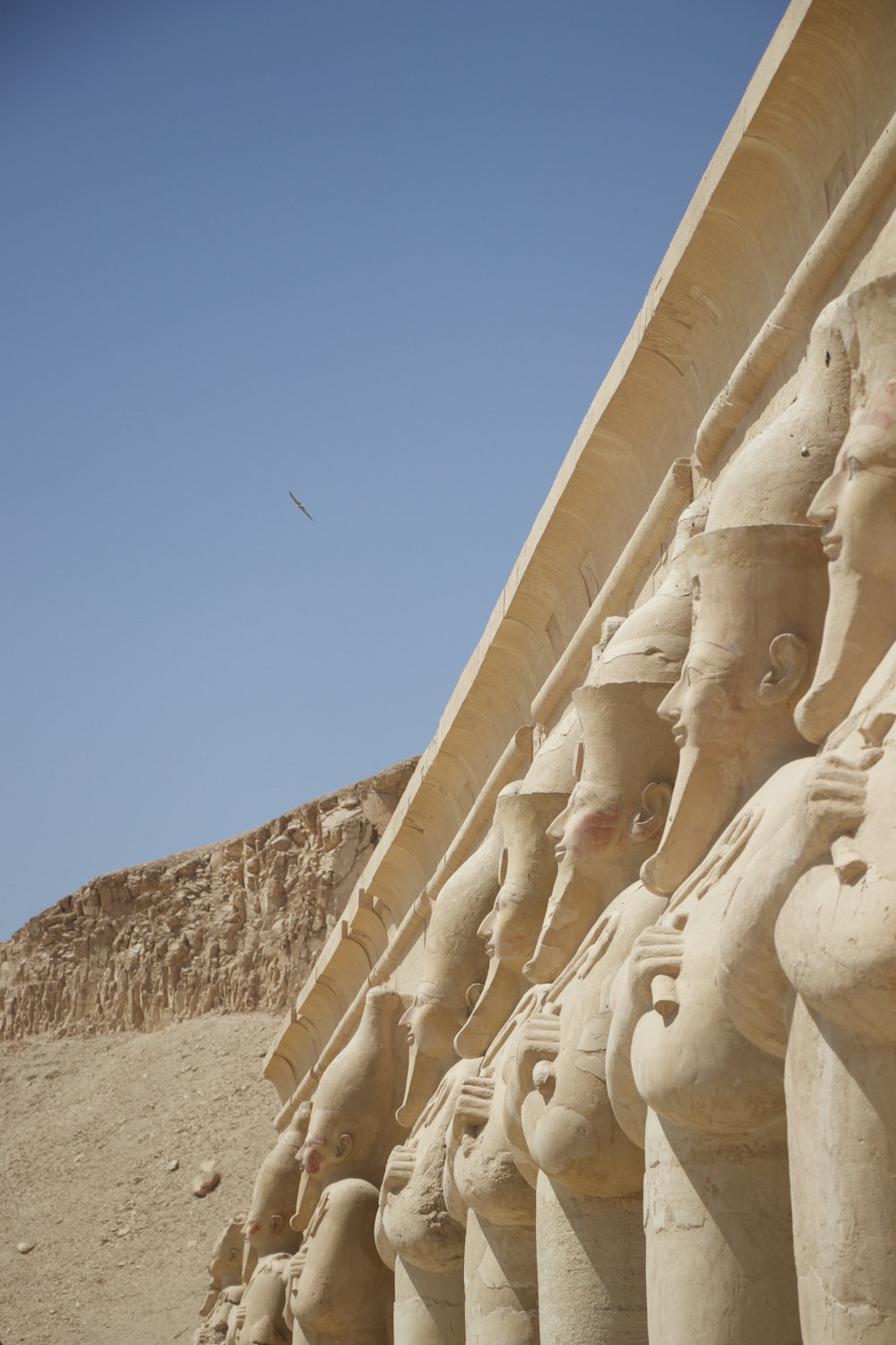 a row of statues in front of a pyramid