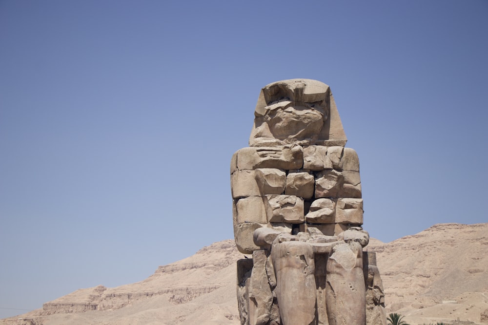 a large statue of a man in front of a mountain