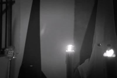 A mysterious figure cloaked in deep purple robes performing a ritual by candlelight.