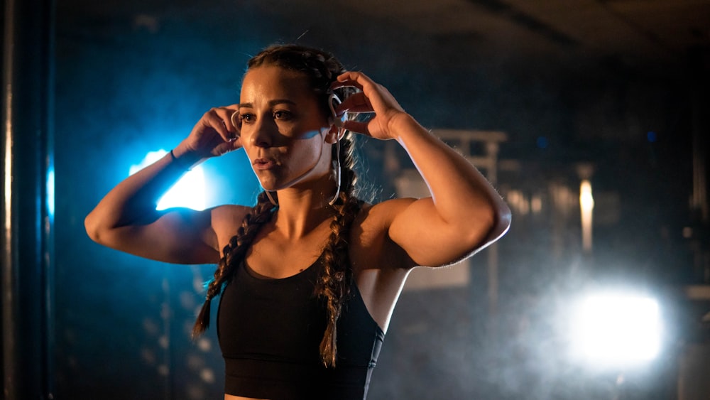 a woman in a black top is holding her hair