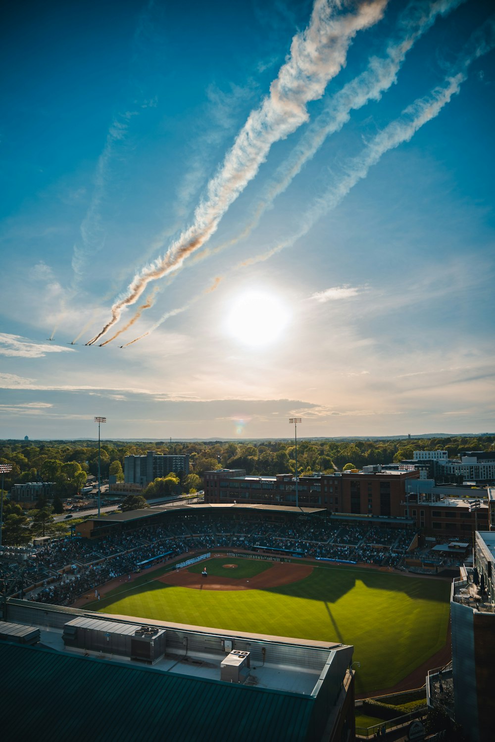 a plane flying over a baseball field with a sky background