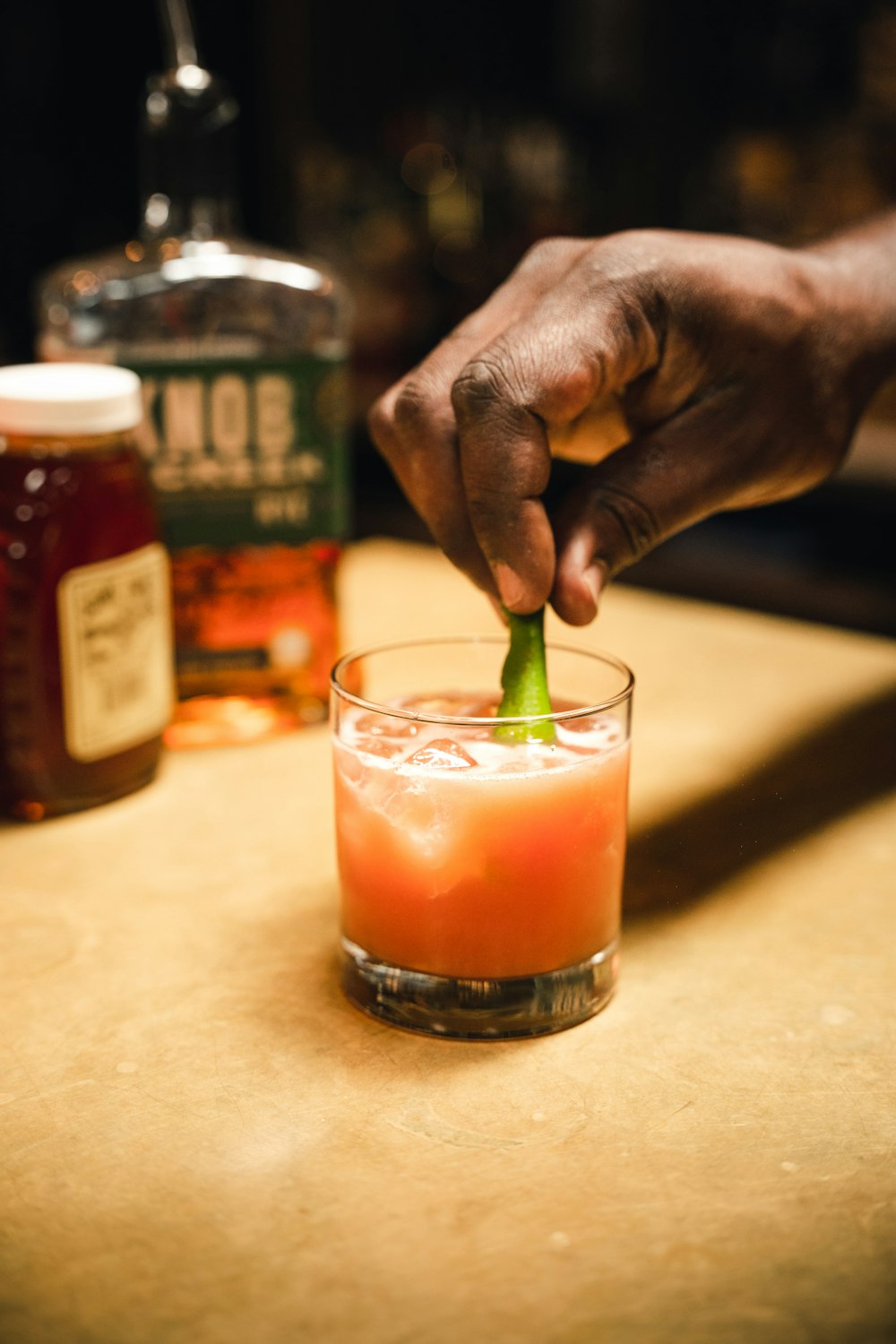 a person putting a green piece of food in a glass