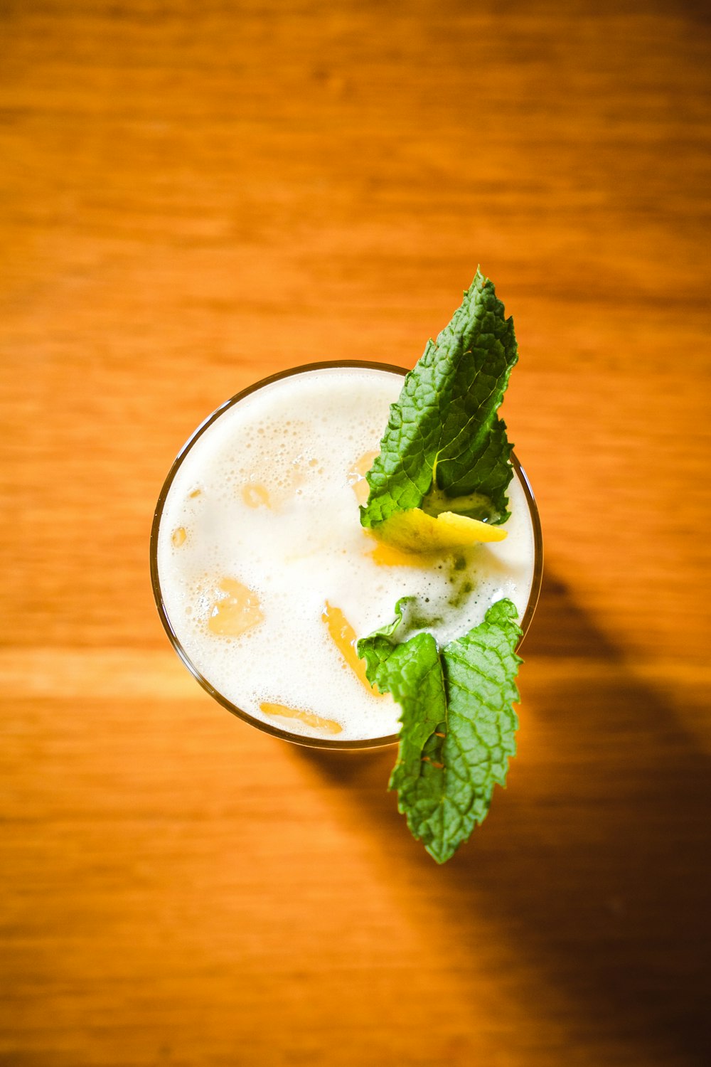 a glass filled with a drink on top of a wooden table